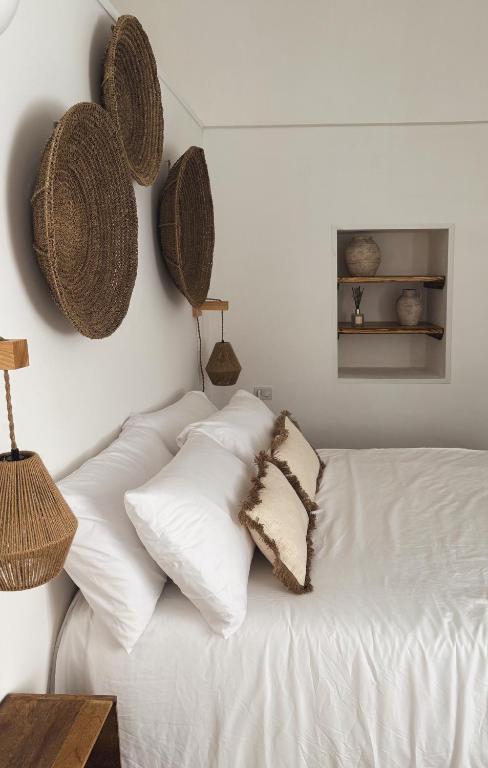 a white bed with white pillows and baskets on the wall at Dimora Pinto in Locorotondo