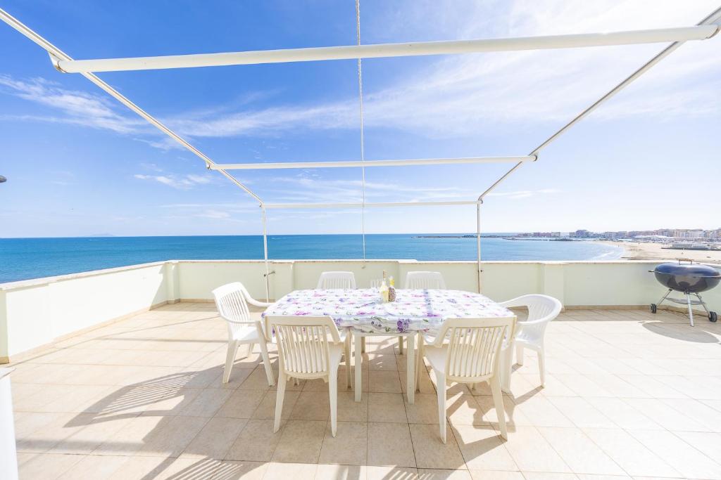 Una mesa y sillas en un balcón con vista al mar. en La casa di Anna, en Nettuno