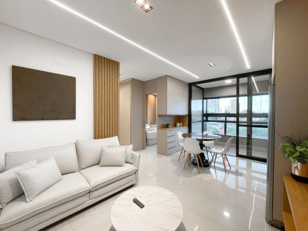 a living room with a white couch and a table at Studio Vista Dourada in Campo Grande