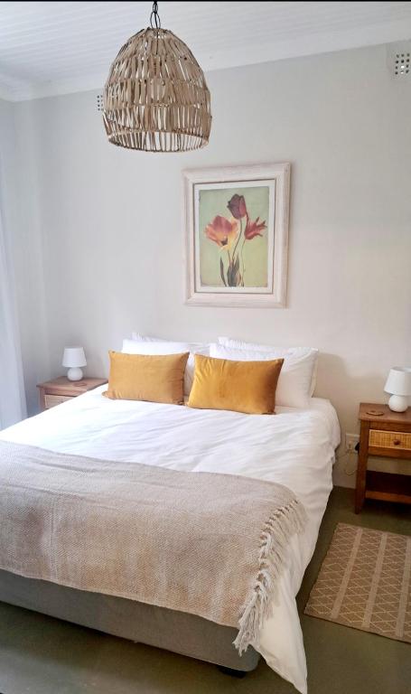 a bedroom with a bed with white sheets and a chandelier at 177 on Church in Oudtshoorn