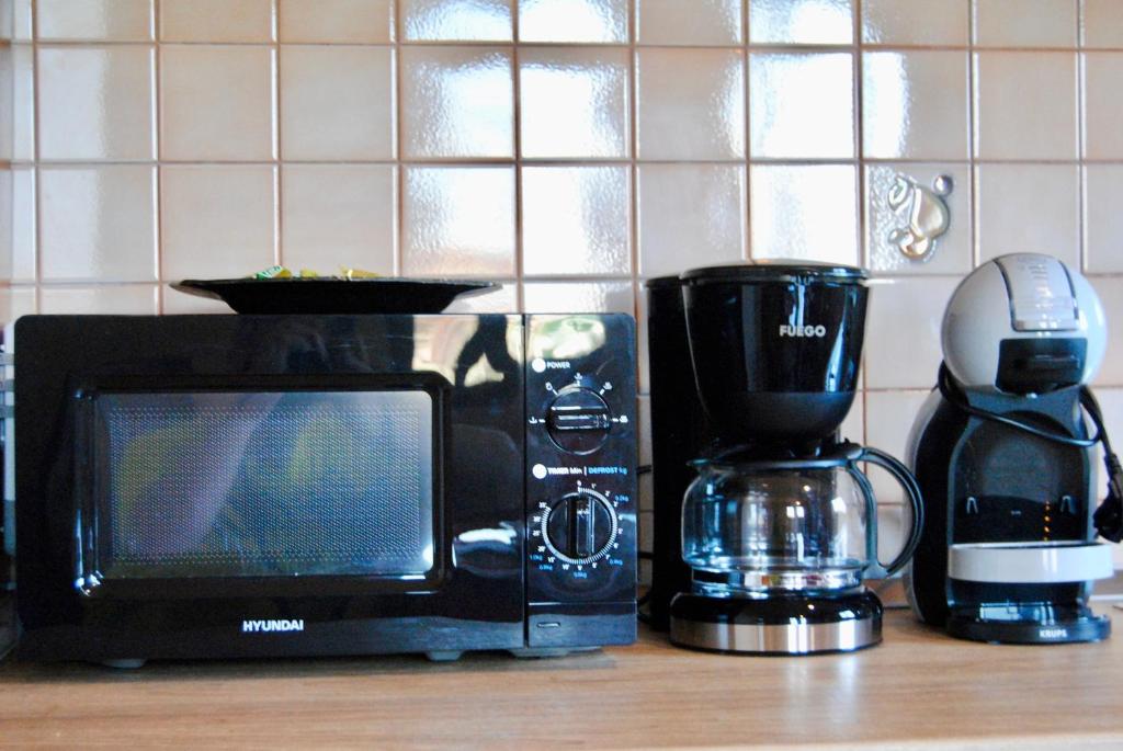 un forno a microonde appoggiato su un bancone accanto a una macchina per il caffè di Demaj House a Grilë