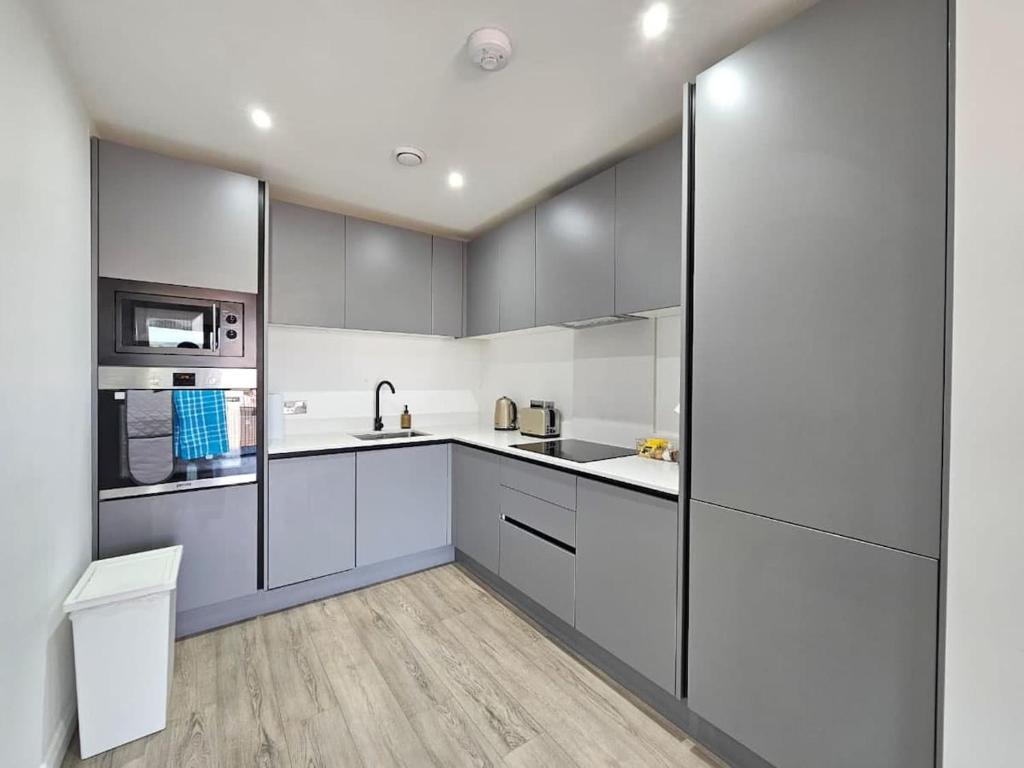 a kitchen with gray cabinets and white appliances at 2 Bedroom Flat in Belfast in Belfast