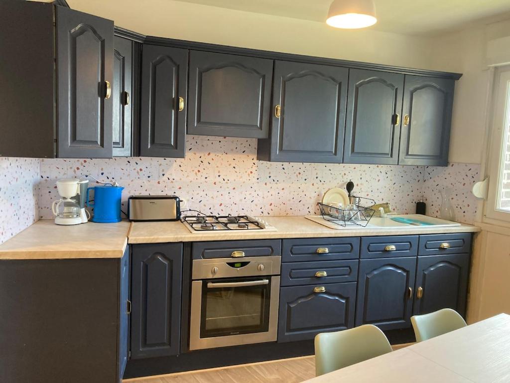 La cuisine est équipée de placards bleus et d'un four avec plaques de cuisson. dans l'établissement Appartement 3 chambres près du CHR, à Loos