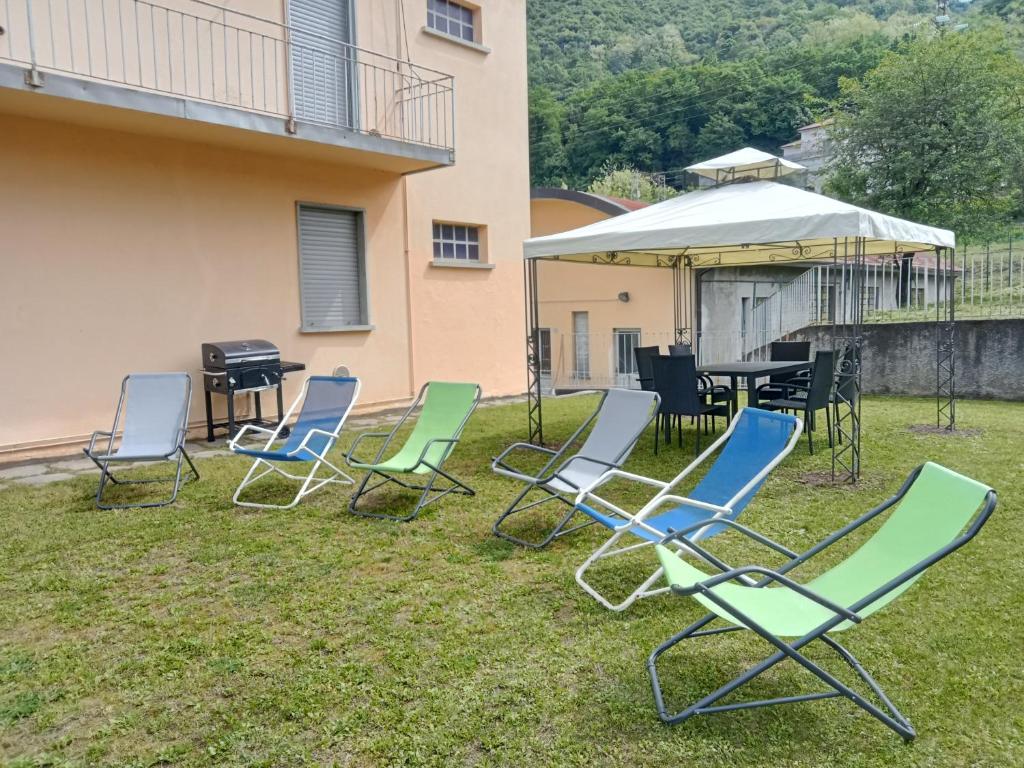 a group of lawn chairs and an umbrella in the grass at Casa dolce casa, a 2 passi dal lago e vicina a Varenna in Lierna