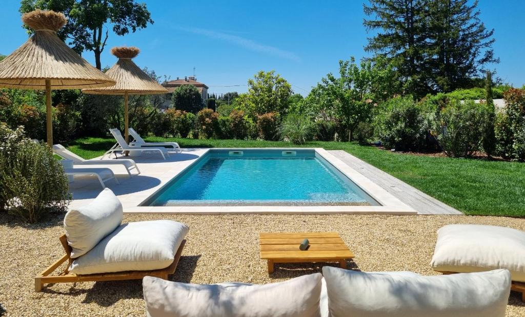 - une piscine dans une cour avec des chaises et un parasol dans l'établissement Centre St Rémy - le Mas Bohème, à Saint-Rémy-de-Provence