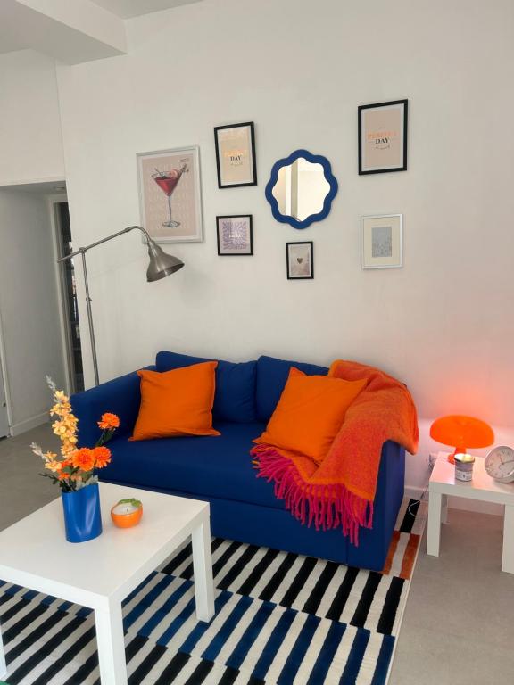 - un canapé bleu avec des oreillers orange dans le salon dans l'établissement T2 RÉNOVÉ avec TERRASSE en HYPER CENTRE de Dijon, à Dijon