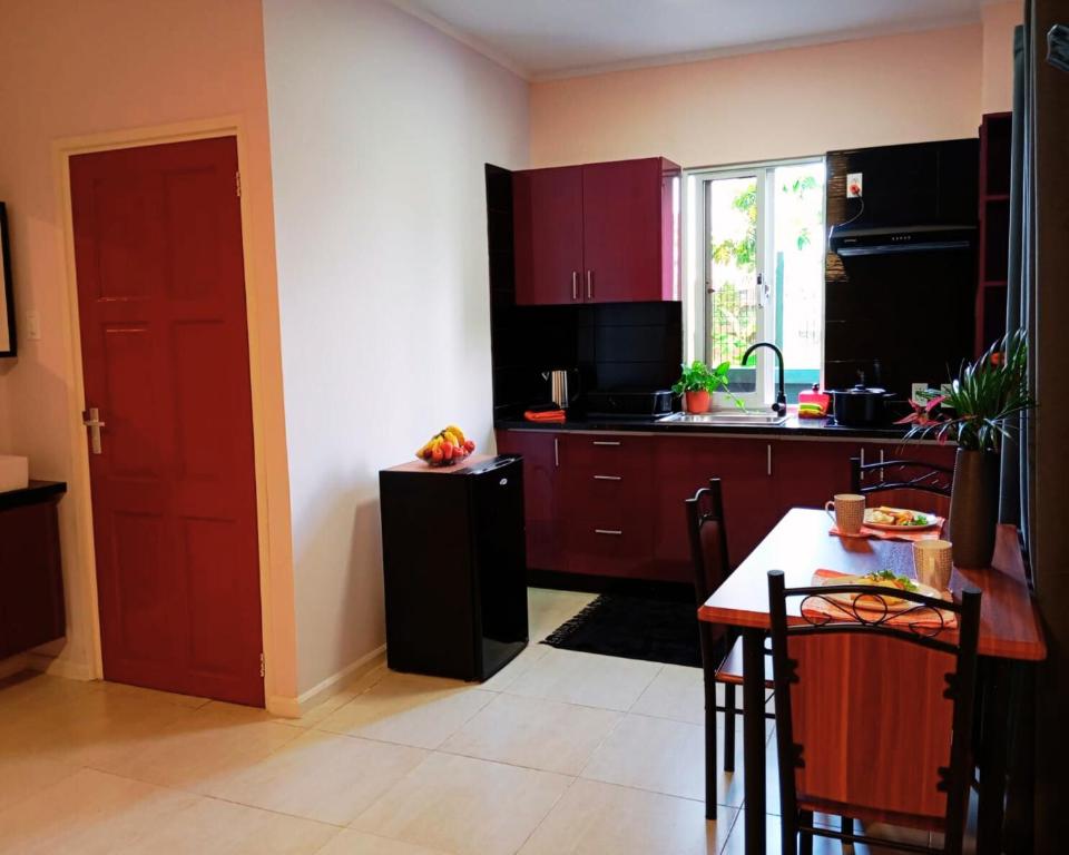 Una cocina con gabinetes rojos y una mesa y una ventana. en Dolfijn Studios, en Paramaribo