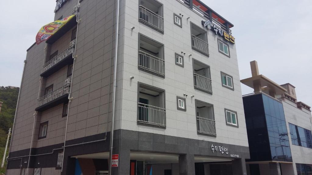 a tall white building with windows on the side of it at Suzy Pension in Yeosu