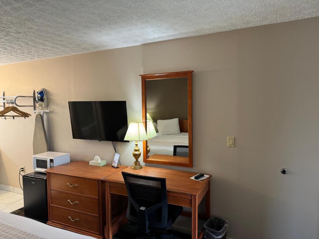 a hotel room with a desk with a bed and a mirror at South Shore Inn in Sandusky