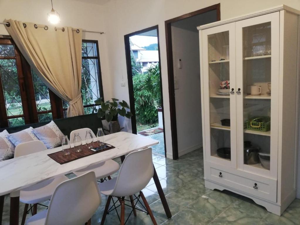 a dining room with a white cabinet and a table and chairs at Chiltern cottages in Amphoe Koh Samui