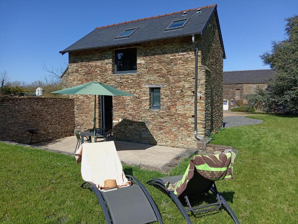 - une table, deux chaises et un parasol dans la cour dans l'établissement gite paisible à la ferme, à Sainte-Honorine-de-Ducy
