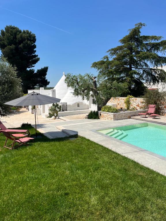 basen z parasolem, krzesłem, stołem i parasolem w obiekcie IL TRULLO BIANCO - Country House & SPA w mieście Castellana Grotte