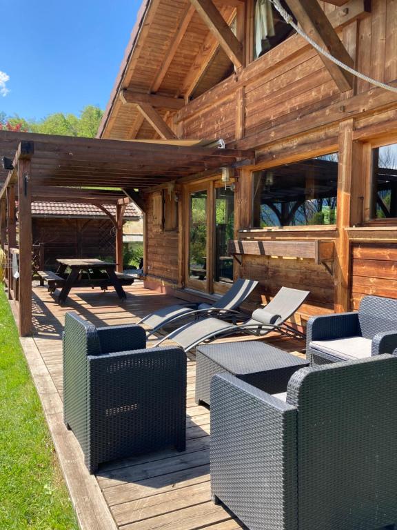 une terrasse en bois avec des chaises et une table de pique-nique dans l'établissement Chalet Cosy avec terrasse plein sud, 2 chambres, au cœur de la Haute-Savoie, à Châtillon-sur-Cluses