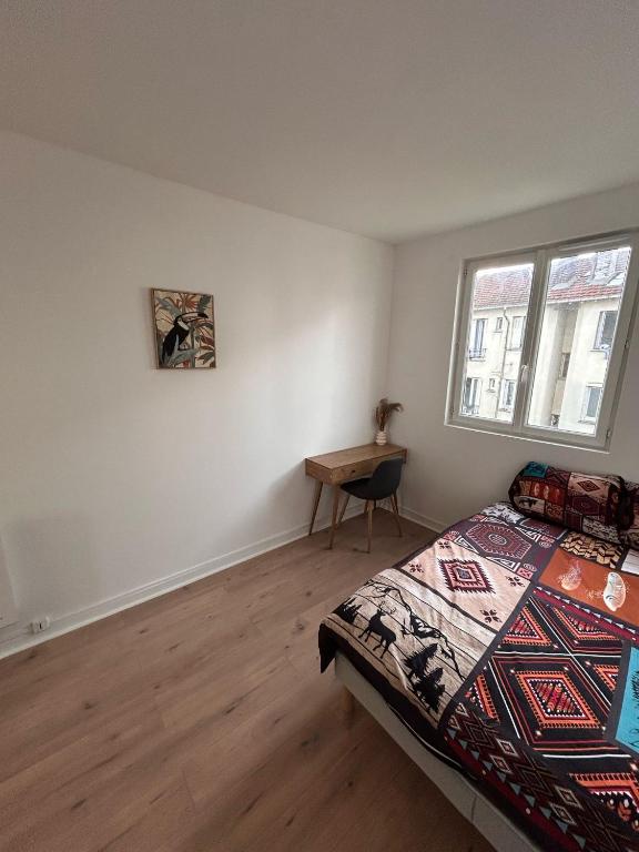 a bedroom with a bed and a table and a window at Studio cosy proche transports in Aulnay-sous-Bois