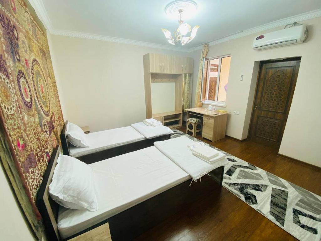 Una habitación con dos camas y una mesa dentro. en Hotel Mashhur, en Bukhara