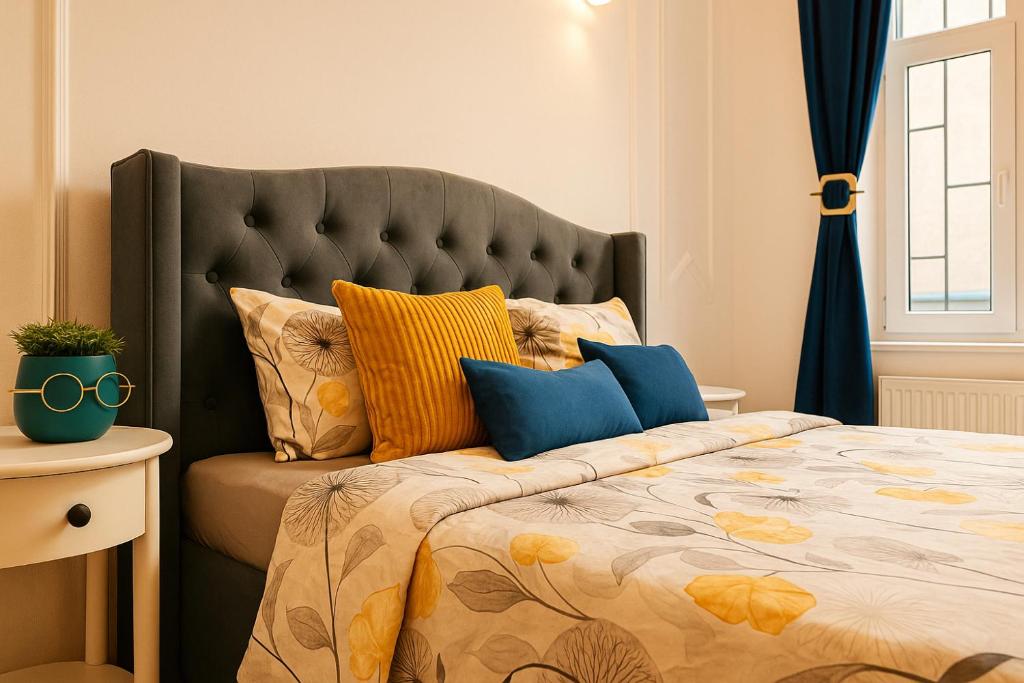 a bedroom with a large bed with yellow and blue pillows at Luxury Ultacental Apartament in Cluj-Napoca