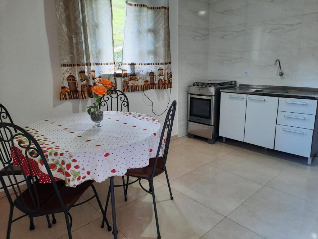 a kitchen with a table and chairs and a stove at Sítio Jabuticabeira in Santo Antônio do Pinhal