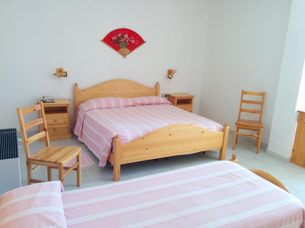 una camera con un letto in legno e due sedie di Hotel Panorama a Badesi