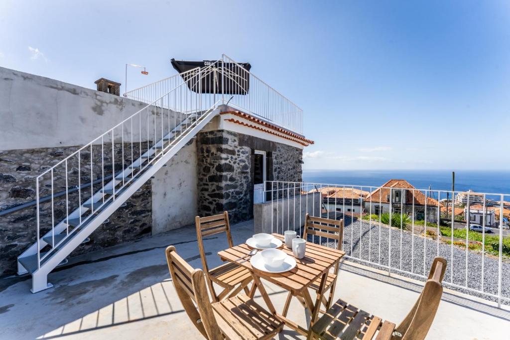 a house with a balcony with a table and chairs at Social Lodge Galinho in Estreito da Calheta