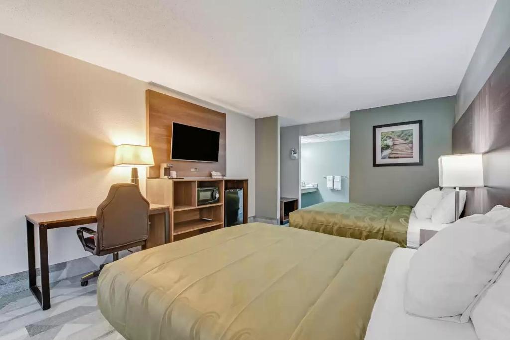 a hotel room with two beds and a desk and a television at Quality Inn in Dalton