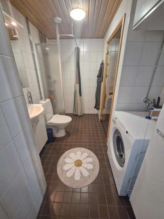 a bathroom with a toilet sink and a washing machine at Cozy one-bedroom apartment with sauna in Rauma