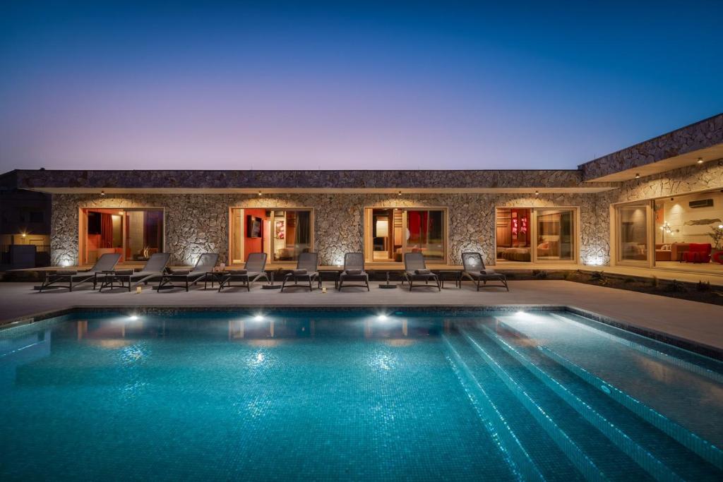 a swimming pool in a house with chairs and lights at NEW! Contemporary Villa Fantazija – A Luxurious Retreat in Dicmo in Dicmo