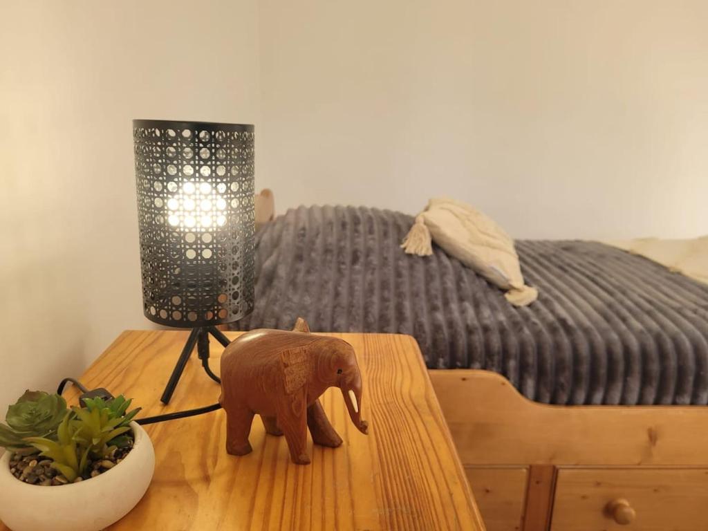 un éléphant en jouet sur une table à côté d'un lit dans l'établissement Maison de campagne normande et accueil chevaux, à Percy