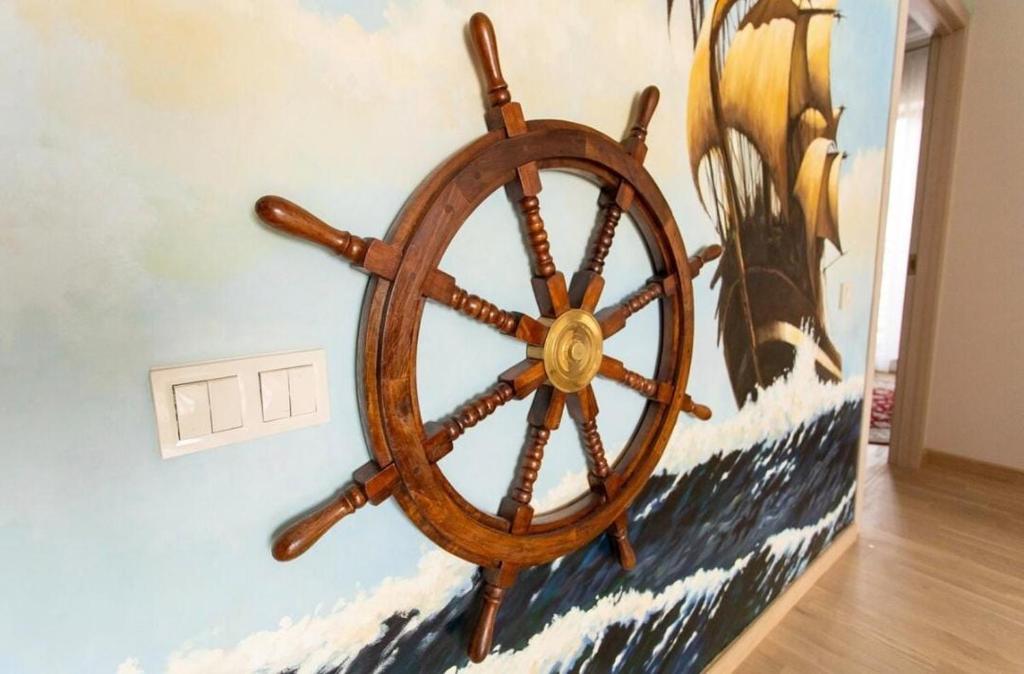 a wooden steering wheel on a wall with a painting at New two bedroomJurmala apartment in Jūrmala