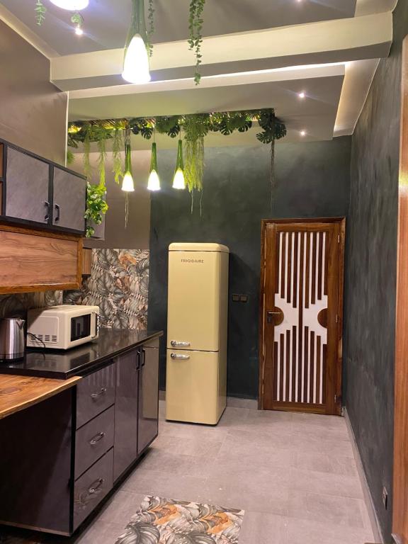 a kitchen with a refrigerator next to a door at Keur lumières in Dakar