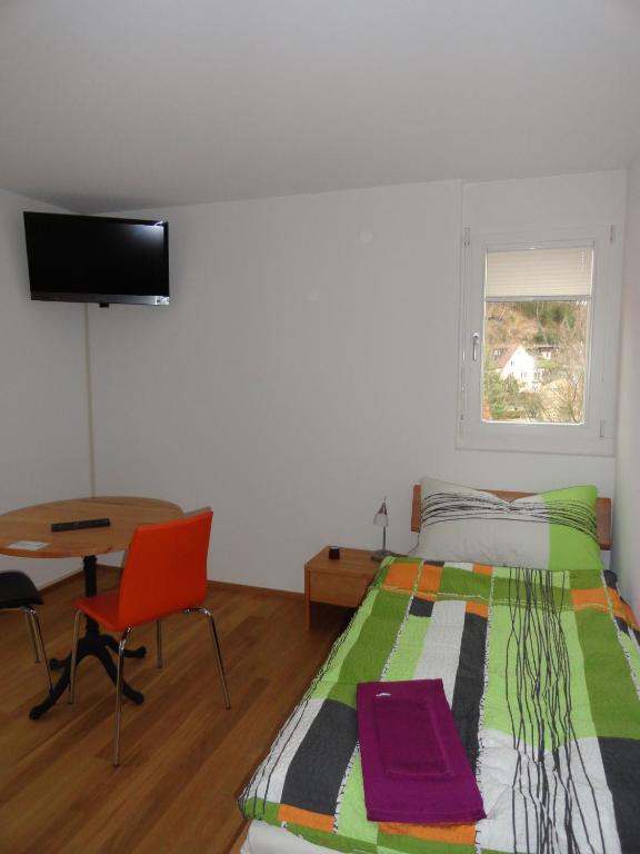 a bedroom with a bed and a desk and a television at Bed and Breakfast Wegmann in Andelfingen