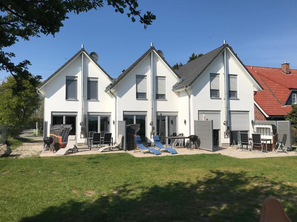 a white house with chairs and tables in front of it at The Fehmarn Lodges - EMOTION - in Fehmarn