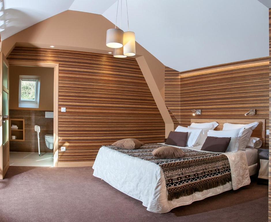 a bedroom with a large bed with a wooden wall at Logis Hotel Du Casino Restaurant Le Mathelia in Vierville-sur-Mer