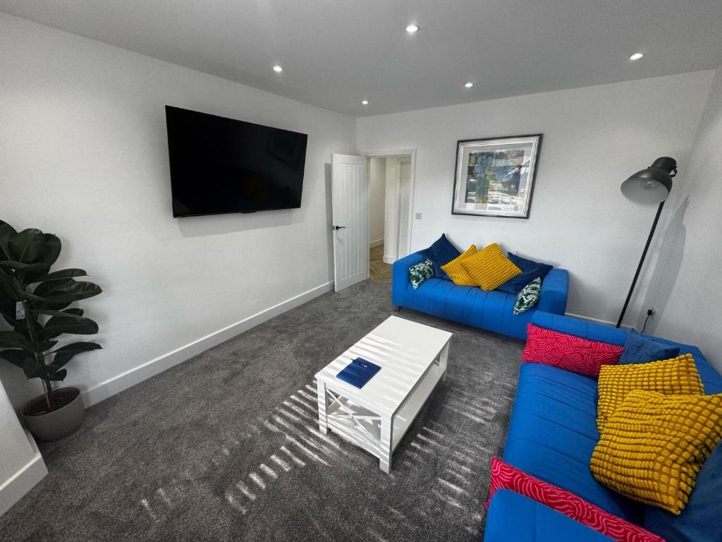 a living room with a blue couch and a tv at Parkview holiday apartments GroundFloor in Skegness
