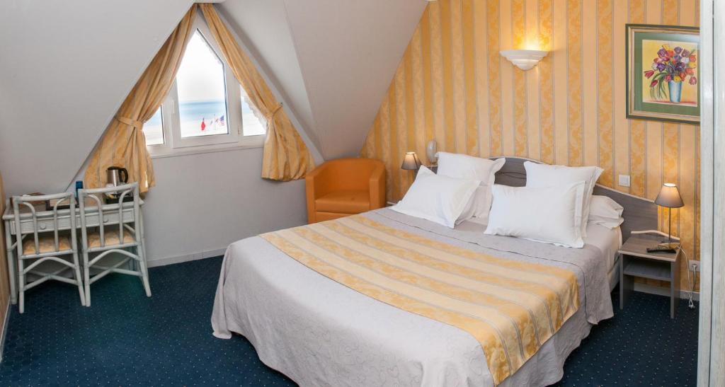 a hotel room with a bed and a crib at Logis Hotel Du Casino Restaurant Le Mathelia in Vierville-sur-Mer