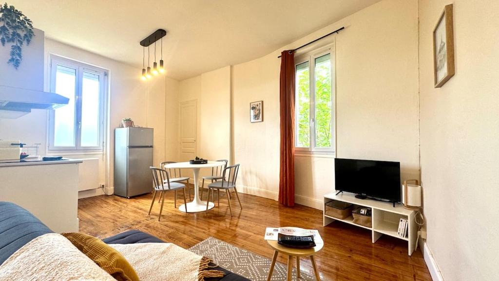 un salon avec un canapé, une télévision et une table dans l'établissement L'Écrin Sévigné - Wi-Fi & Near Train Station, à Valence
