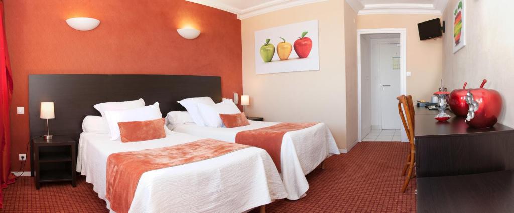 a hotel room with two beds with orange walls at Logis Hotel Du Casino Restaurant Le Mathelia in Vierville-sur-Mer