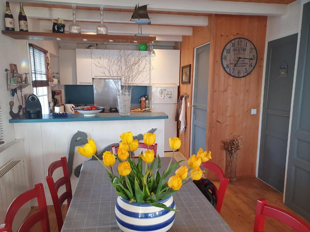 une table avec un vase de fleurs jaunes sur elle dans l'établissement Maison de famille, à Saint-Clément-des-Baleines