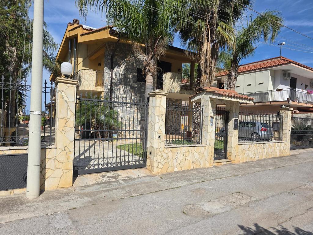 płot przed domem z palmami w obiekcie Villa Aurora Per Vacanze w mieście Palermo