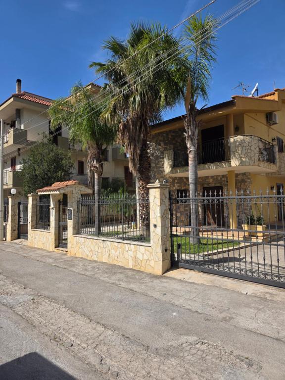 płot przed domem z palmami w obiekcie Villa Aurora Per Vacanze w mieście Palermo