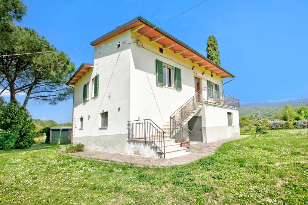 una pequeña casa blanca con una escalera en un campo en Cozy Counrtry House, en Terranuova Bracciolini