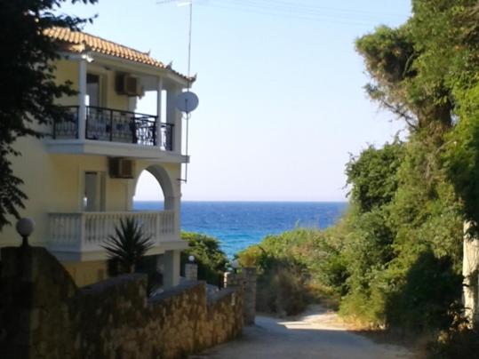a house on a hill next to the ocean at Anemone Blue Seaside Apartments in Zakynthos Town