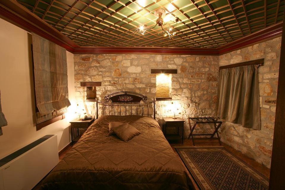 - une chambre avec un lit dans une pièce dotée de murs en pierre dans l'établissement Hagiati Guesthouse, à Ioannina