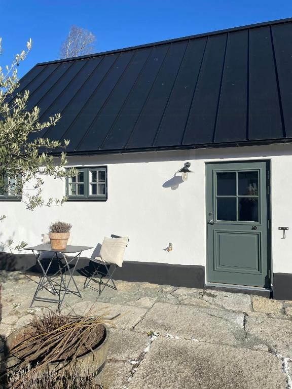 a house with a black roof with a green door at Traditional Scanian Farm In The Fields Of Österlen in Gärsnäs