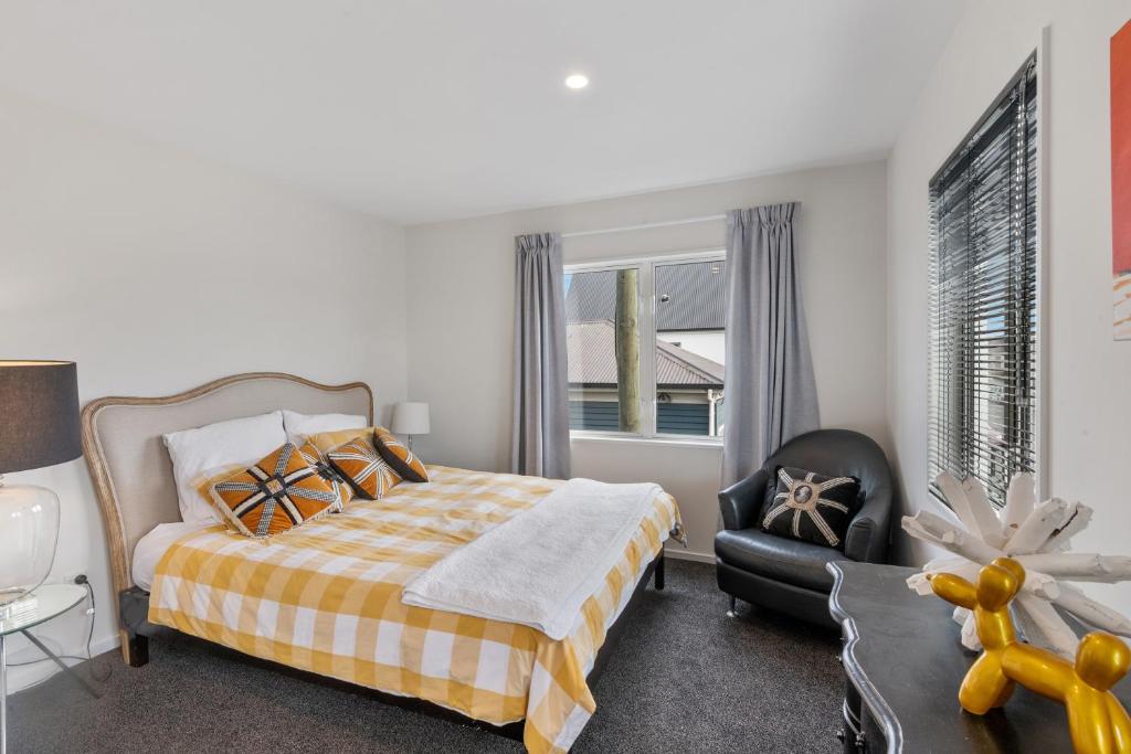 Un dormitorio con una cama y una silla y una ventana. en Central City Comfort and Style, en Christchurch
