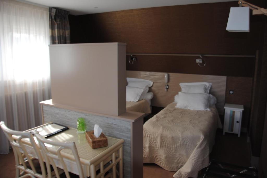 a hotel room with a bed and a table with a chair at Logis Hotel Du Casino Restaurant Le Mathelia in Vierville-sur-Mer