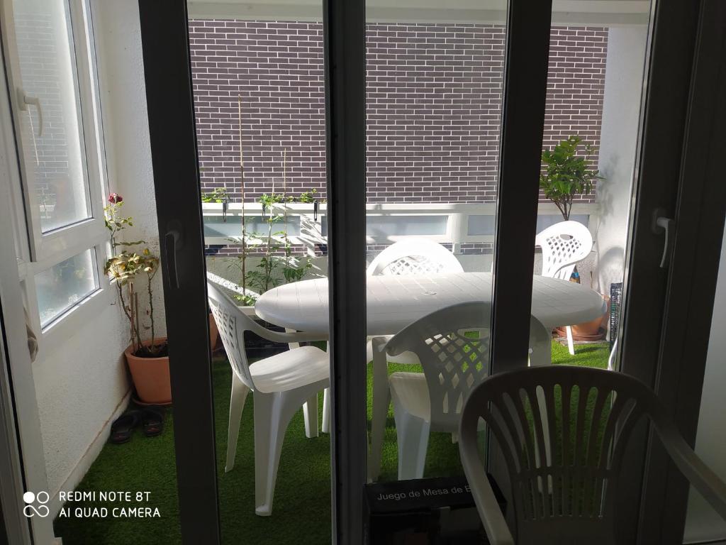 a table and chairs in a room with a window at Etxalo, apartamento con terraza en Gorliz in Górliz-Elexalde
