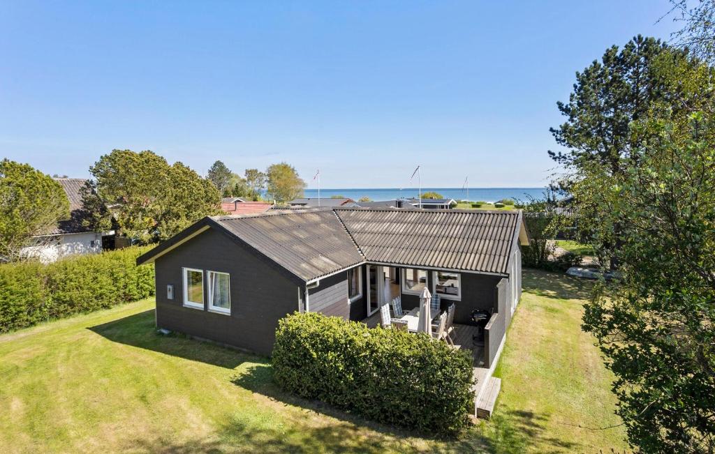 a black house on a yard with the ocean in the background at 3 Bedroom Beautiful Home In Hesselager in Hesselager