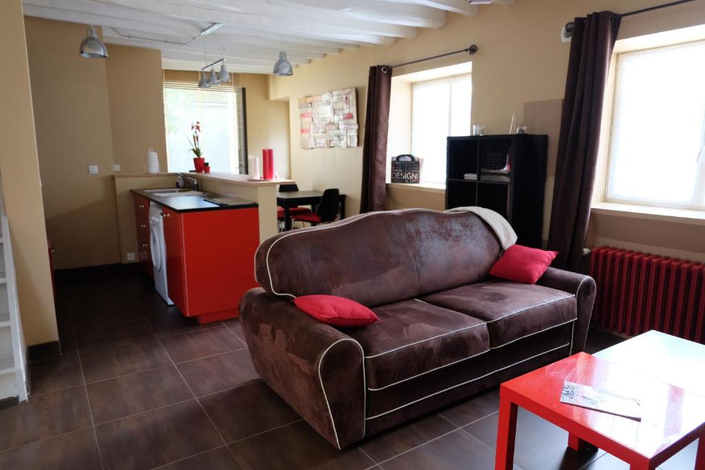 a living room with a brown couch and a kitchen at Gite de Charme in Villeneuve-sur-Auvers