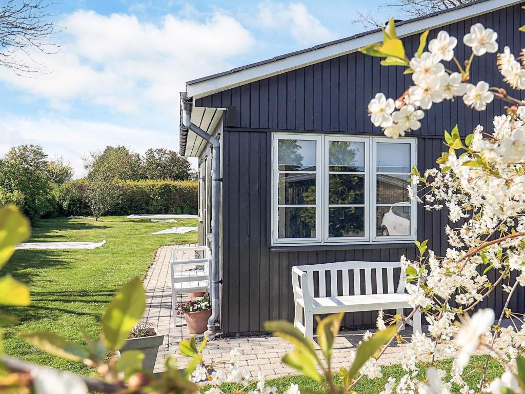 a black house with a white bench in a yard at Cozy Summer House Near Ore Strand in Vordingborg