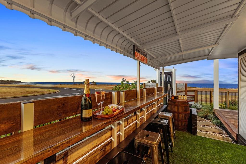 a bar with a bottle of wine and a plate of food at Quirky Black Shack in Burnett Heads